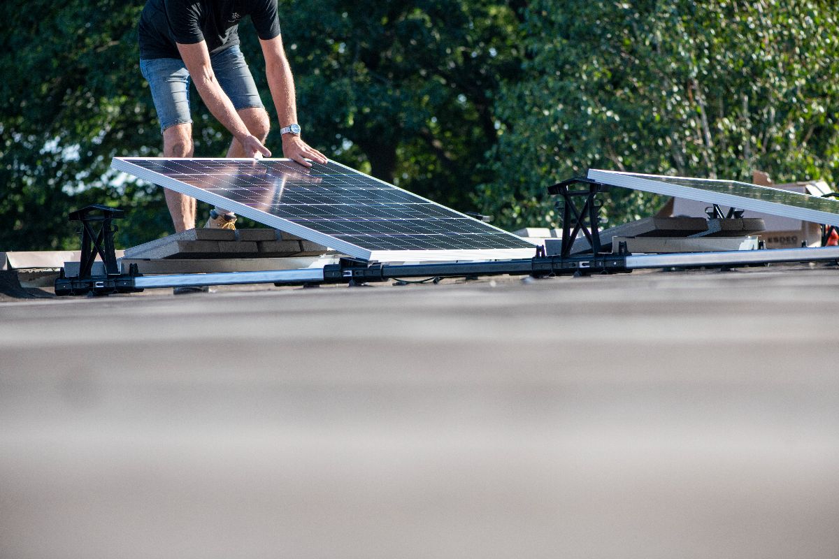 A man laying down solar panels on the roof of a sustinable home in the Philippines
